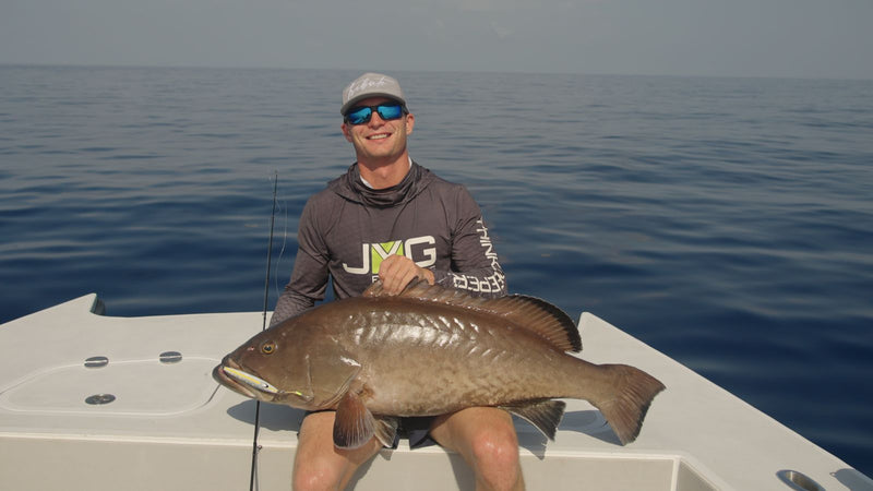 Angler holding a gag grouper on the bow of a center console offshore Florida